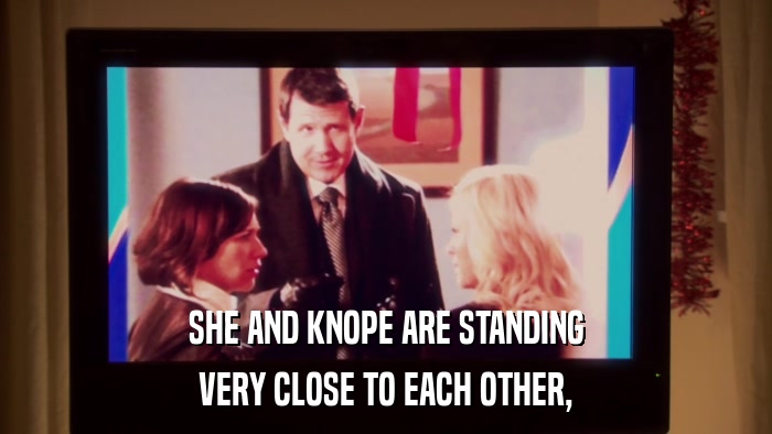 SHE AND KNOPE ARE STANDING VERY CLOSE TO EACH OTHER, 
