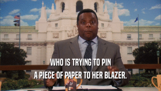 WHO IS TRYING TO PIN A PIECE OF PAPER TO HER BLAZER. 