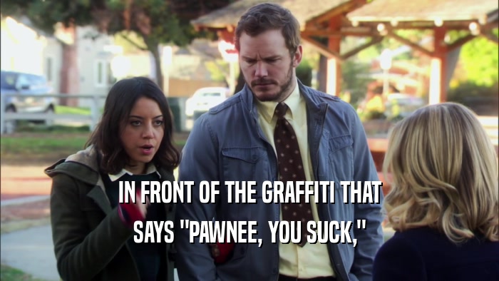 IN FRONT OF THE GRAFFITI THAT SAYS 