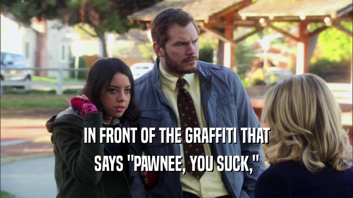 IN FRONT OF THE GRAFFITI THAT SAYS 