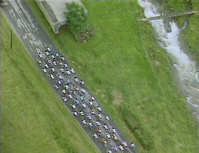 YOU JOIN ME IN THE HELICOPTER,
 AS WE LOOK DOWN ON THESE CYCLISTS
 