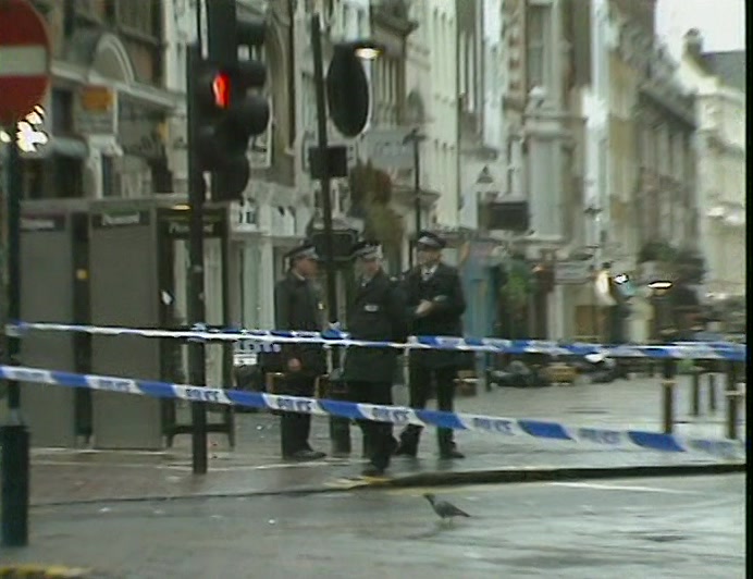 OXFORD STREET IN LONDON, WITH THREE POLICEMEN
 AND A KNOTTED TAPE BARRIER.
 