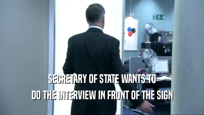 SECRETARY OF STATE WANTS TO DO THE INTERVIEW IN FRONT OF THE SIGN 